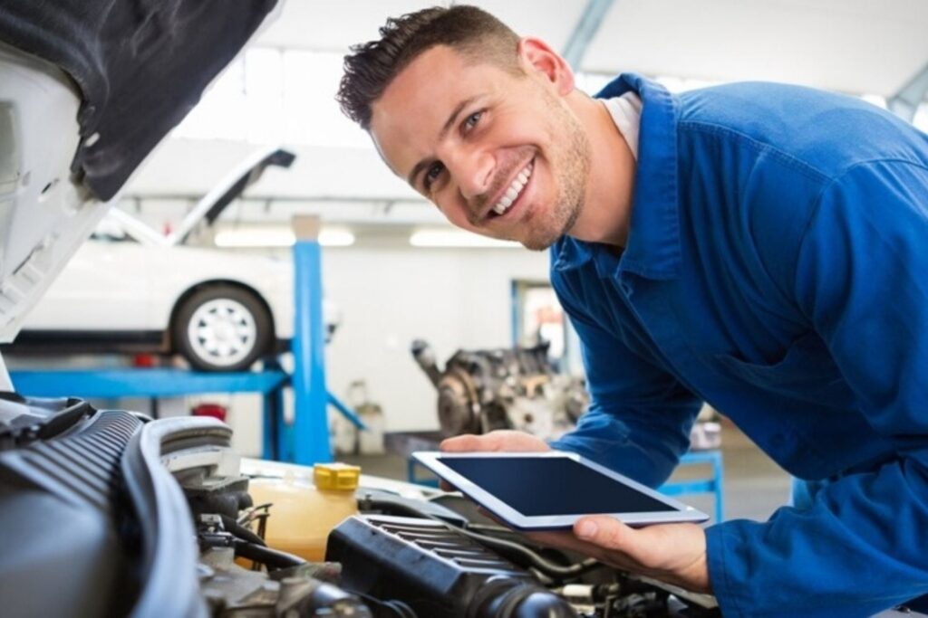 man smiling at camera whilst doing car repairs