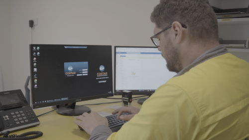 man seated at a desk working on a computer with dual screens